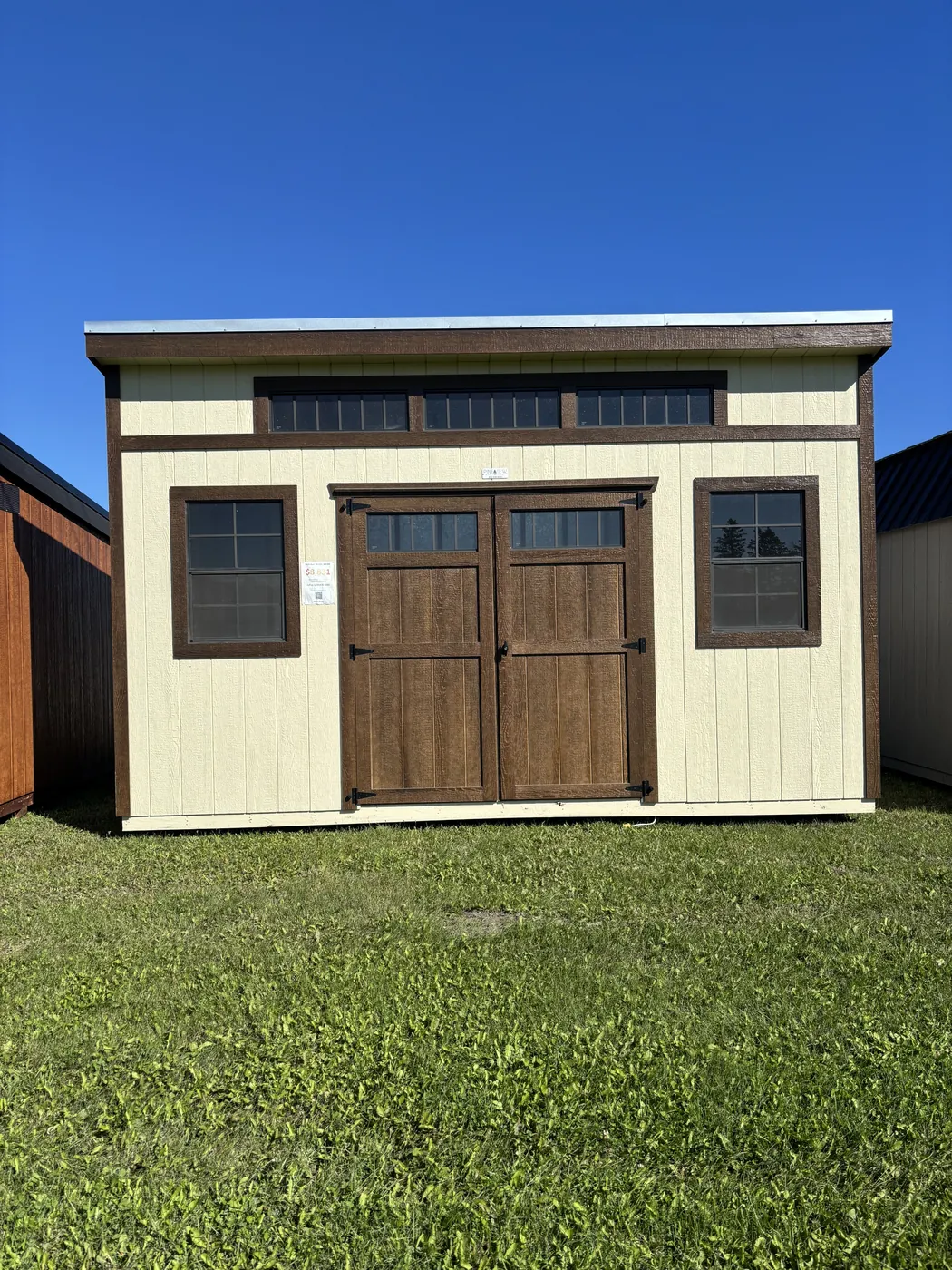 Cream modern shed with brown double doors and transom windows at Borderland Powersports, Portage la Prairie MB