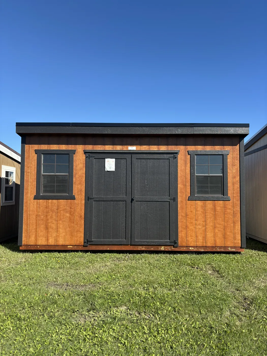 Stained wood modern shed with black double doors at Borderland Powersports, Portage la Prairie MB