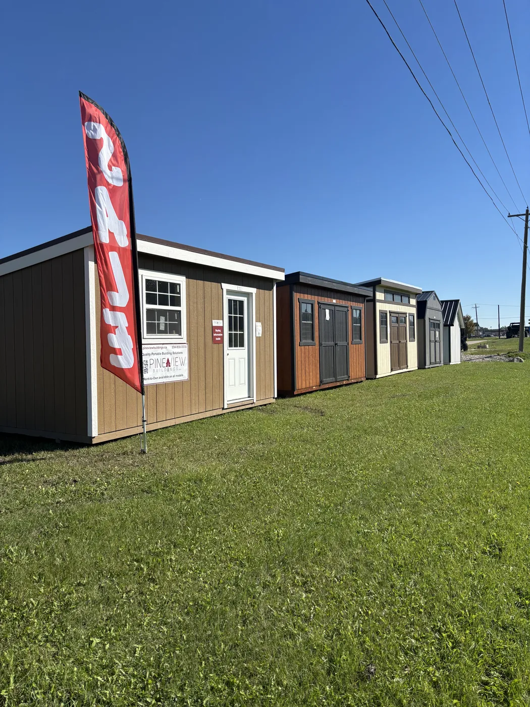 Pine View storage sheds lined up on the display lot at Borderland Powersports, Portage la Prairie MB